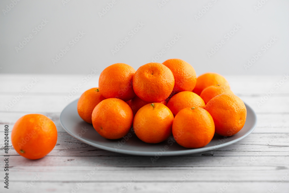 Plate of mandarins on a light wooden background
