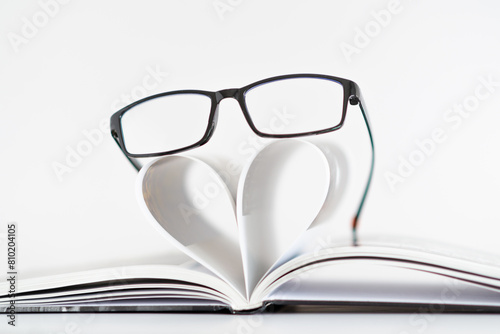A pair of glasses is placed on top of a heart-shaped paper
