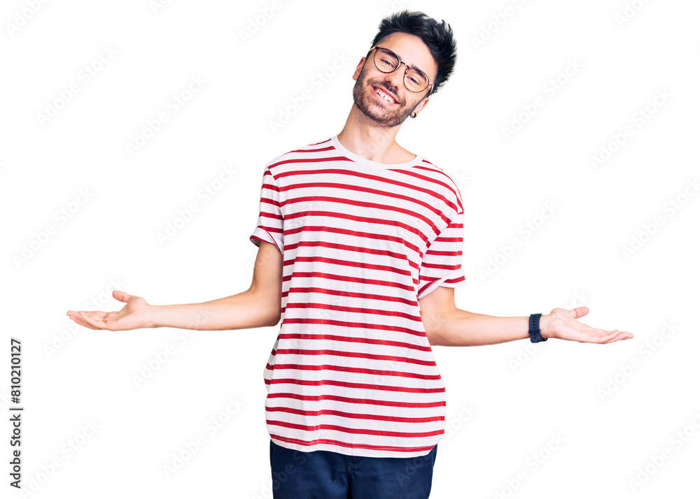 Young hispanic man wearing casual clothes smiling showing both hands open palms, presenting and advertising comparison and balance Young hispanic man wearing casual clothes smiling showing both hands open palms, presenting and advertising comparison and balance