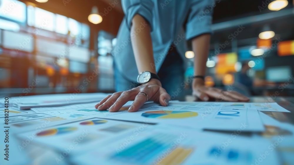 A detailed shot shows a person's hand strategizing over financial charts and business plans