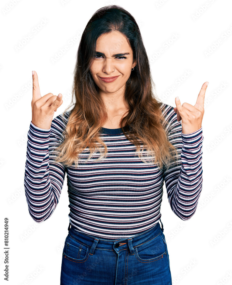 Beautiful hispanic woman wearing casual striped shirt shouting with crazy expression doing rock symbol with hands up. music star. heavy concept. Beautiful hispanic woman wearing casual striped shirt shouting with crazy expression doing rock symbol with hands up. music star. heavy concept.