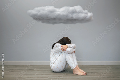 Unrecognizable woman with mental disorder and suicidal thoughts crying sitting under a dark cloud on her room. Negative emotions and bad feelings concept.