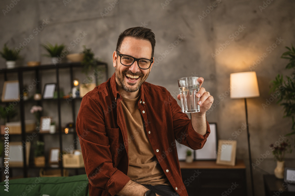 Portrait of adult caucasian man sit and hold glass of water at home Portrait of adult caucasian man sit and hold glass of water at home