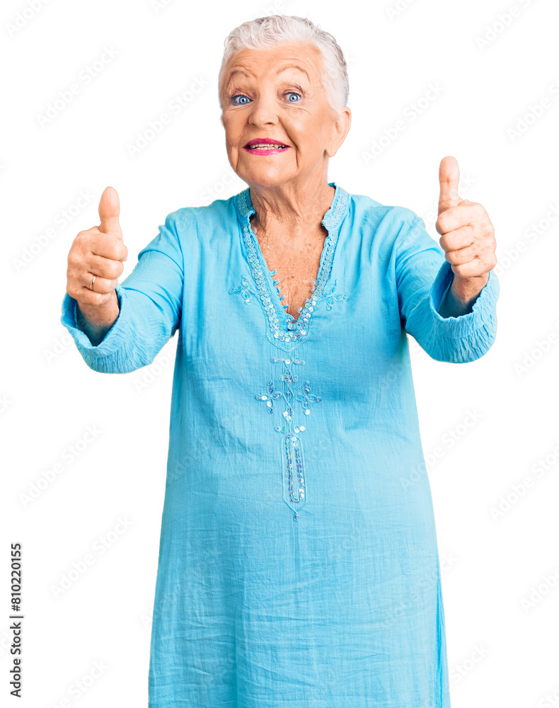 Senior beautiful woman with blue eyes and grey hair wearing summer dress approving doing positive gesture with hand, thumbs up smiling and happy for success. winner gesture. Senior beautiful woman with blue eyes and grey hair wearing summer dress approving doing positive gesture with hand, thumbs up smiling and happy for success. winner gesture.