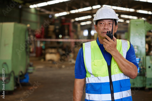 senior worker talking on walkie talkie in the factory