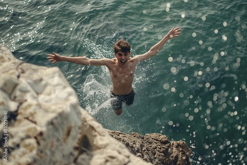 A young man excitedly diving into the ocean from a rocky outcrop, surrounded by the exhilaration of the plunge and the splash of water, the scene softly blurred
