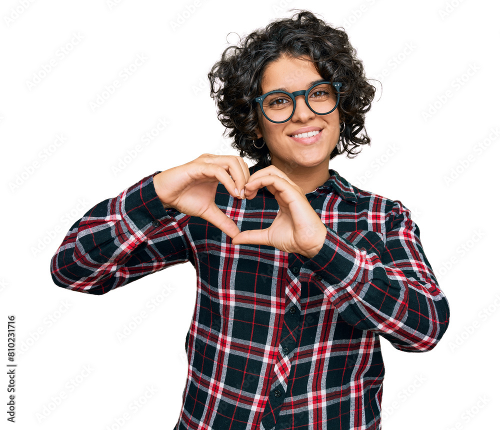 Young hispanic woman with curly hair wearing casual clothes and glasses smiling in love showing heart symbol and shape with hands. romantic concept. Young hispanic woman with curly hair wearing casual clothes and glasses smiling in love showing heart symbol and shape with hands. romantic concept.