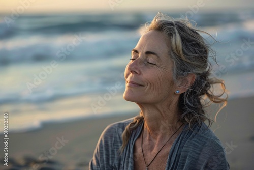 A middle-aged woman peacefully meditating on a secluded beach, attuned to the sound of waves and the salty scent of the sea breeze