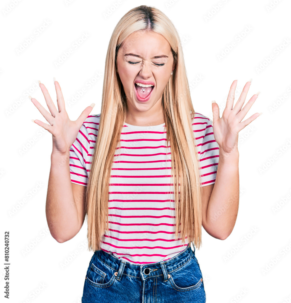 Beautiful blonde woman wearing casual striped t shirt celebrating mad and crazy for success with arms raised and closed eyes screaming excited. winner concept Beautiful blonde woman wearing casual striped t shirt celebrating mad and crazy for success with arms raised and closed eyes screaming excited. winner concept