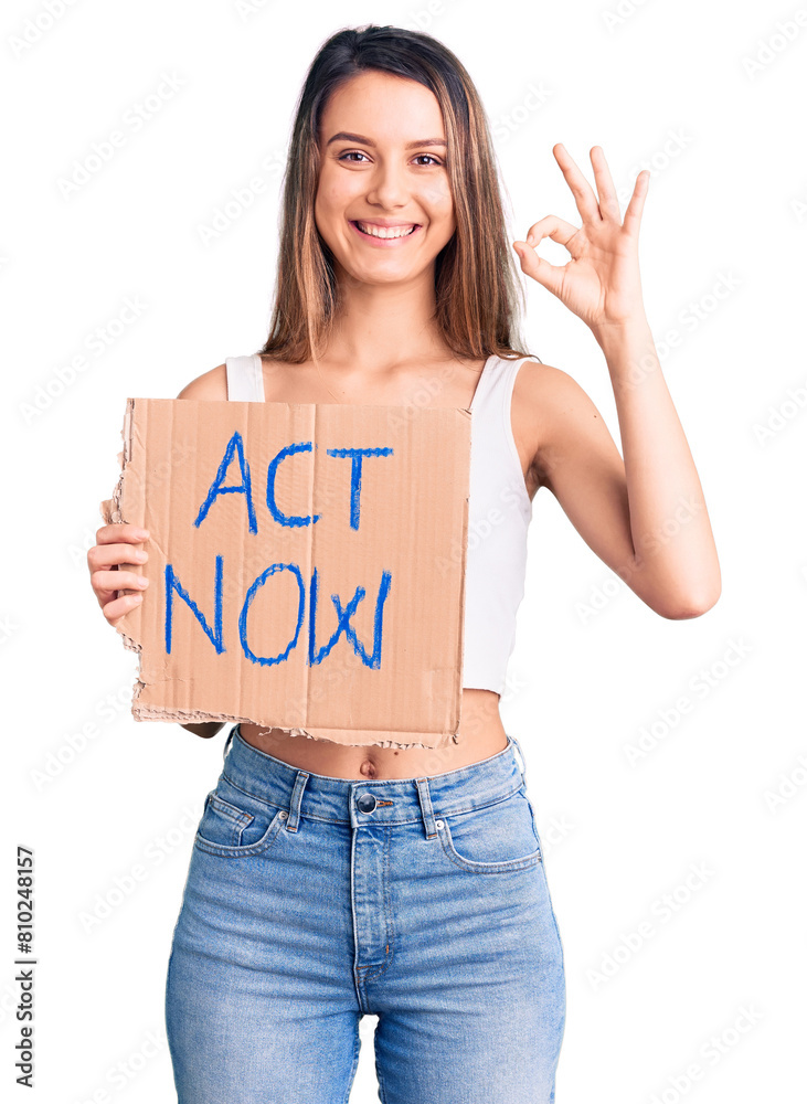 Young beautiful girl holding act now banner doing ok sign with fingers, smiling friendly gesturing excellent symbol Young beautiful girl holding act now banner doing ok sign with fingers, smiling friendly gesturing excellent symbol