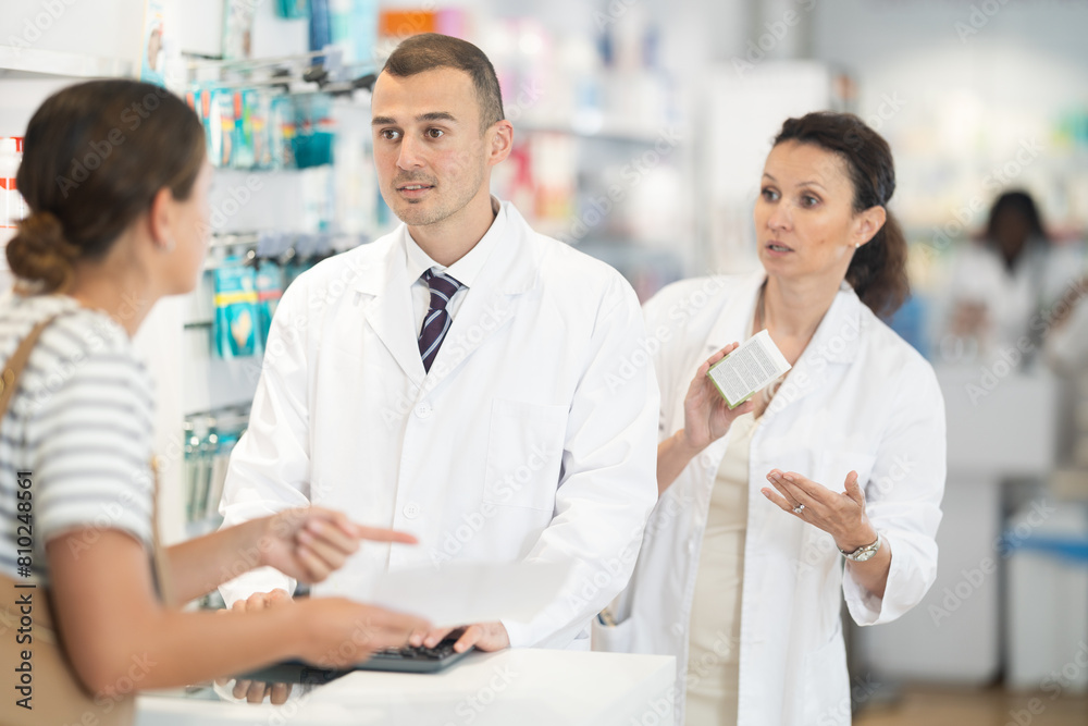 Two pharmacists offer a girl medicine for pain in a pharmacy