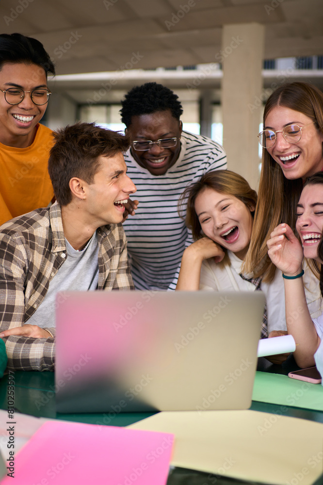 Vertical Group of young diverse students people laughing using laptop in the cafeteria on the university campus. Multiracial classmates working on a creative college project and studying together Vertical Group of young diverse students people laughing using laptop in the cafeteria on the university campus. Multiracial classmates working on a creative college project and studying together