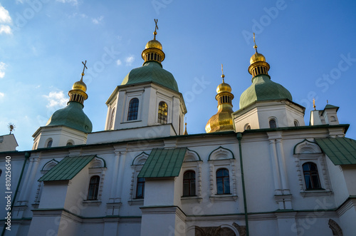 Image of the Saint Sophia Cathedral in Kyiv with crosses  that adorn the pinnacle of each green and gold domes against a backdrop of a serene sky adorned with soft clouds