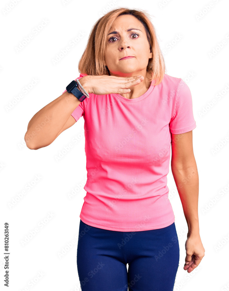 Young blonde woman wearing sportswear cutting throat with hand as knife, threaten aggression with furious violence Young blonde woman wearing sportswear cutting throat with hand as knife, threaten aggression with furious violence