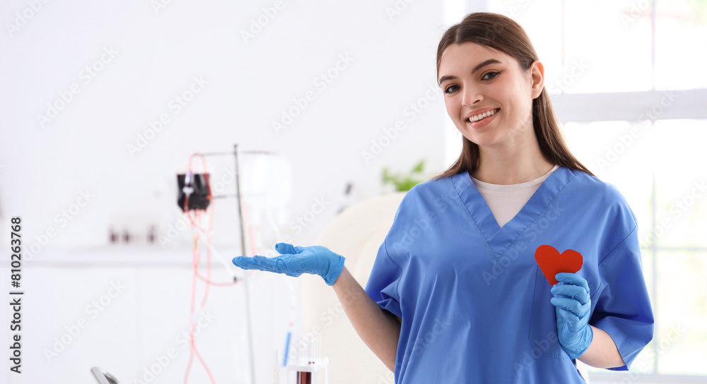 Female nurse with paper heart showing something in clinic Female nurse with paper heart showing something in clinic