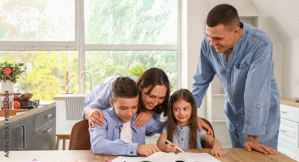 Little children with their parents doing homework in kitchen Little children with their parents doing homework in kitchen