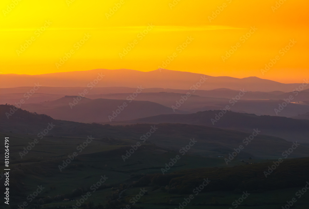Forests of Romania. Aerial wide landscape photo of an amazing orange sunrise golden light over a forest from the hills of Transylvania region from Romania. Travel to Romania.
