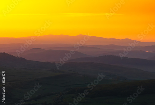 Forests of Romania. Aerial wide landscape photo of an amazing orange sunrise golden light over a forest from the hills of Transylvania region from Romania. Travel to Romania.