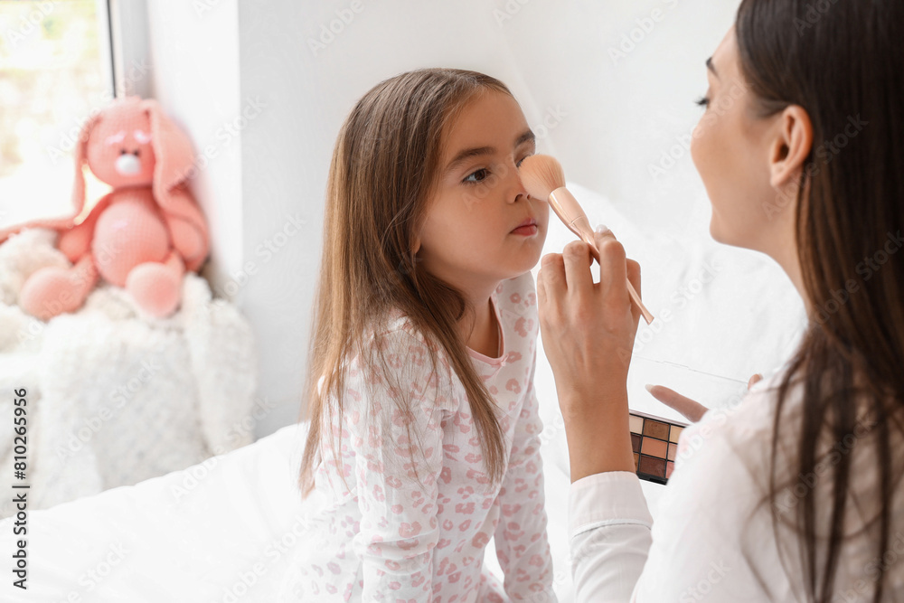Happy mother with her little daughter doing makeup in bedroom, closeup