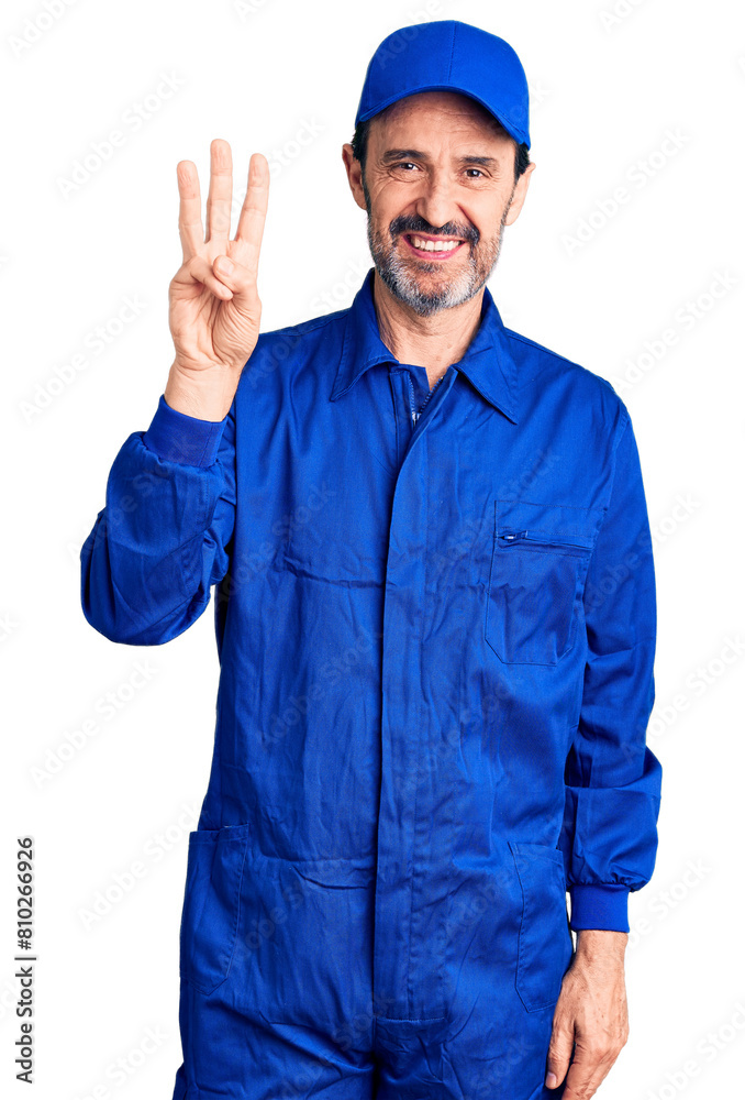 Middle age handsome man wearing mechanic uniform showing and pointing up with fingers number three while smiling confident and happy. Middle age handsome man wearing mechanic uniform showing and pointing up with fingers number three while smiling confident and happy.