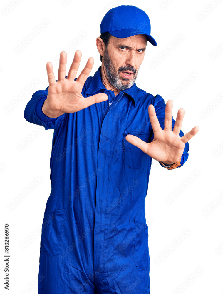 Middle age handsome man wearing mechanic uniform doing stop gesture with hands palms, angry and frustration expression Middle age handsome man wearing mechanic uniform doing stop gesture with hands palms, angry and frustration expression