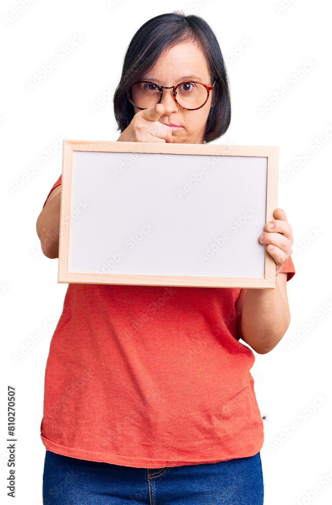 Brunette woman with down syndrome holding empty white chalkboard pointing with finger to the camera and to you, confident gesture looking serious Brunette woman with down syndrome holding empty white chalkboard pointing with finger to the camera and to you, confident gesture looking serious