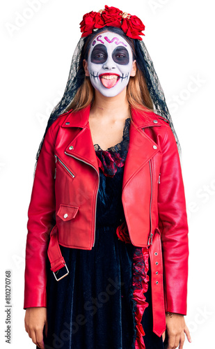 Woman wearing day of the dead costume over background sticking tongue out happy with funny expression. emotion concept.