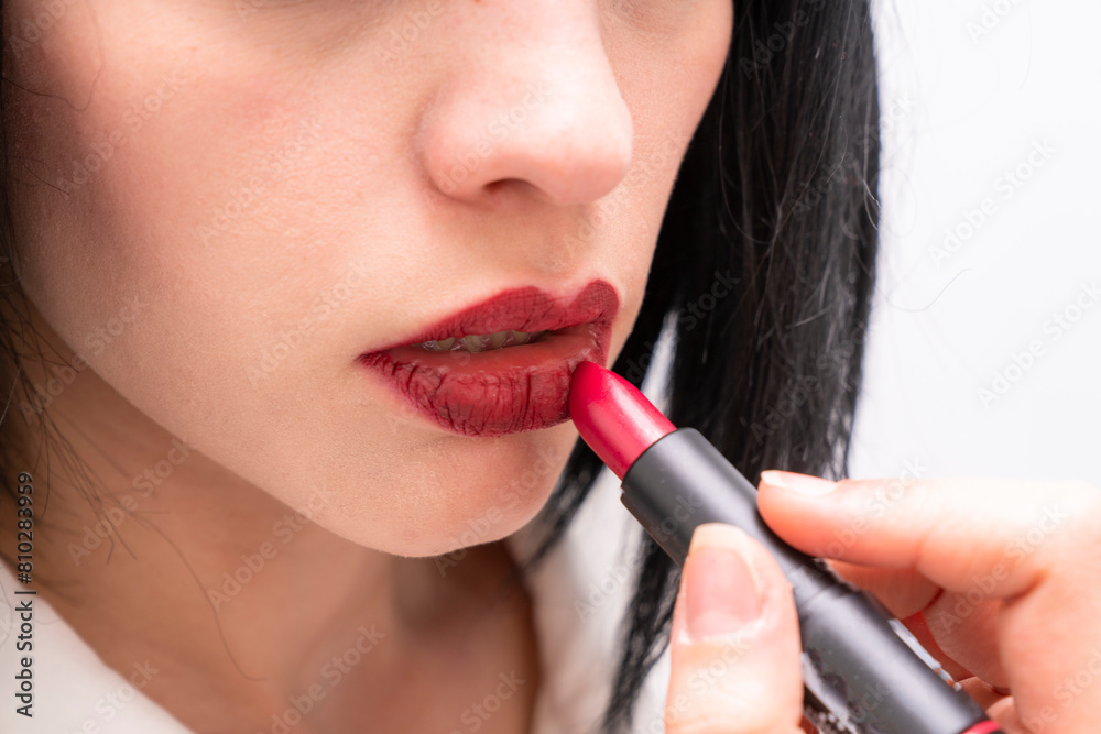 Close-up of black-haired woman applying red lipstick