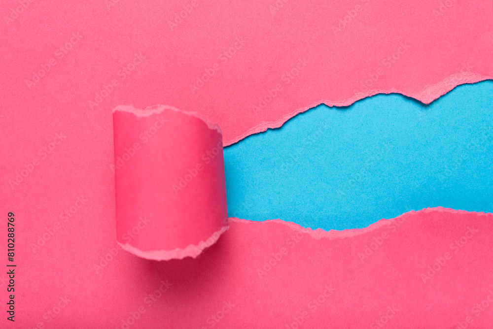 Obraz premium Pink torn paper revealing blue background. Space for text.