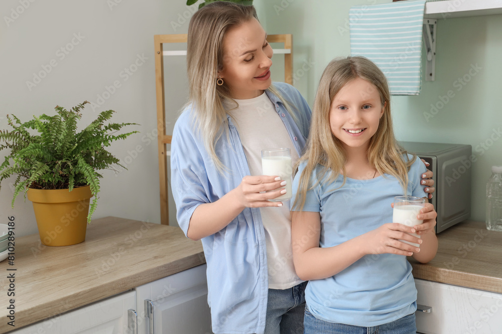 Fototapeta premium Happy daughter and her mother with cups of milk in kitchen