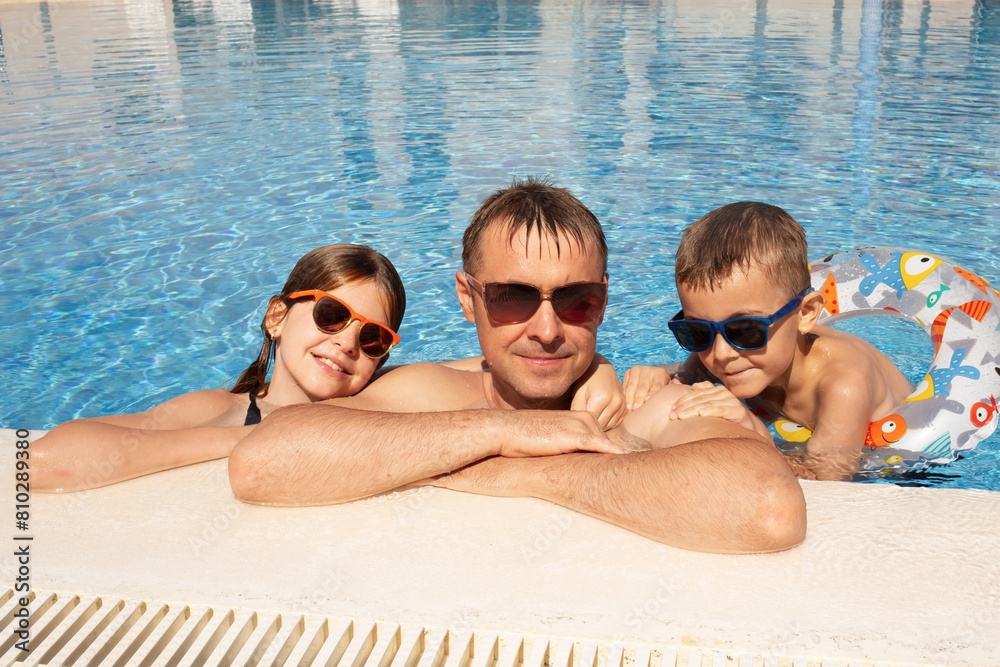happy parents with children playing and having fun in the pool during the holidays. family vacation at the resort. blue background happy parents with children playing and having fun in the pool during the holidays. family vacation at the resort. blue background