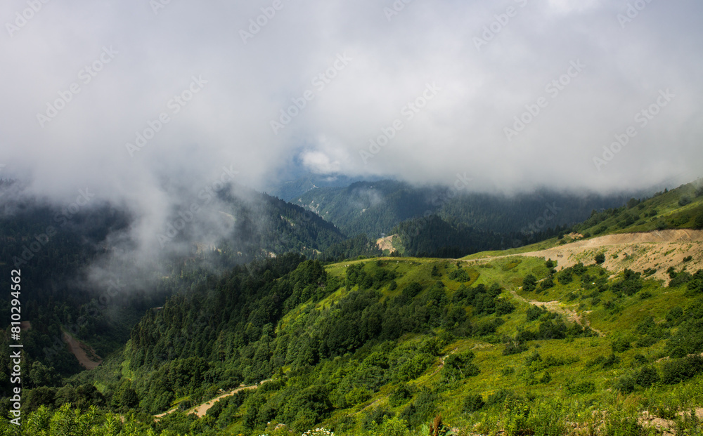 The natural background is beautiful green hills with a white cloud and a copy space on Krasnaya Polyana in Russia The natural background is beautiful green hills with a white cloud and a copy space on Krasnaya Polyana in Russia