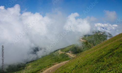 The natural background is beautiful green hills with a white cloud and a copy space on Krasnaya Polyana in Russia