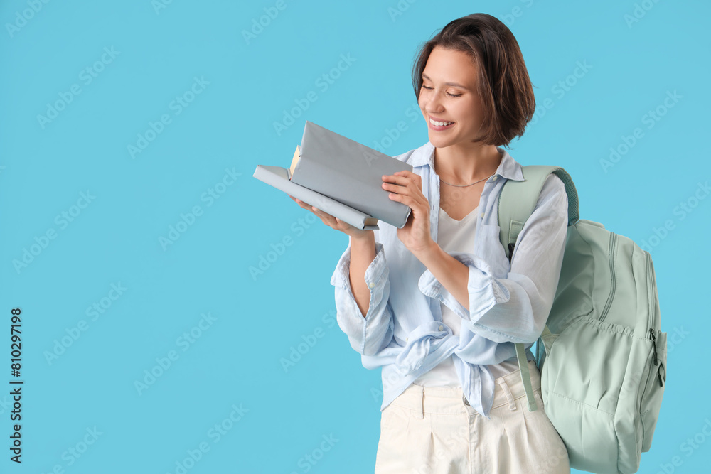 Happy female student with backpack and books on blue background Happy female student with backpack and books on blue background