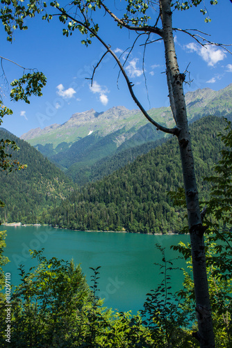 Bright turquoise lake Ritsa in Abkhazia among green hills on a sunny summer day