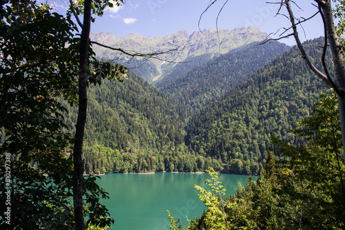 Bright turquoise lake Ritsa in Abkhazia among green hills on a sunny summer day