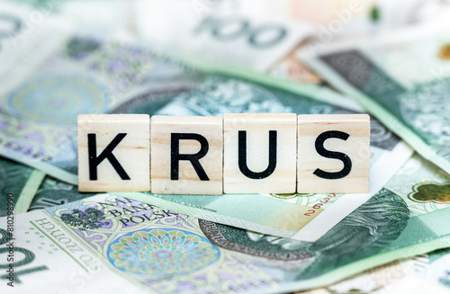 Close-up of Scrabble letters spelling "KRUS" arranged on a colourful background of Polish zloty banknotes