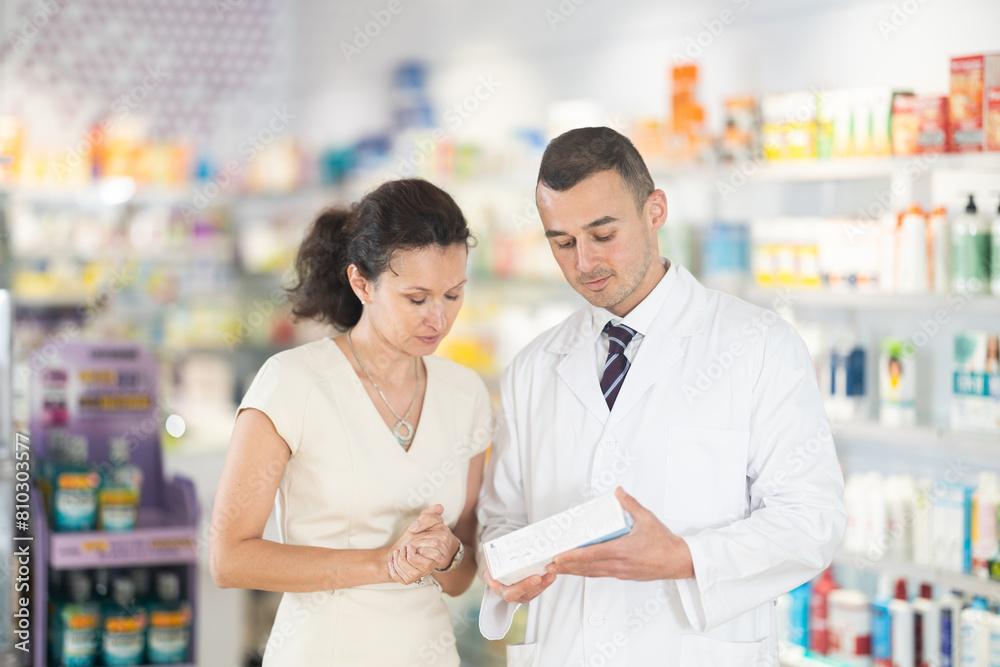 Man pharmacist helps woman buyer to decide on choice an effective medicine