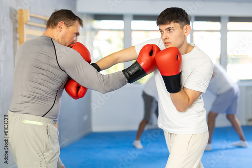 Guy and man sparring partners during training battle fight using technique of boxing match. Boxing section for men, sport as lifestyle