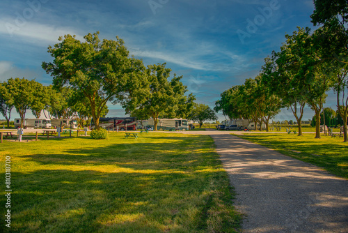 Rv motorhomes parked at campsites in the park with dirt road and trees 