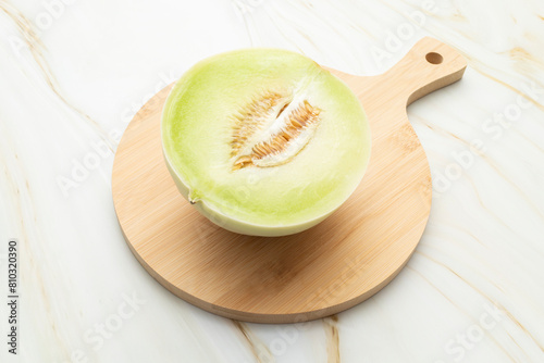 Cut Organic Honeydew Melon On Wooden Cutting Board on Granite Table, Cucumis Melo Inodorus Group. Ripe Nutritious Summer Juicy Fruit. Horizontal Plane. Harvesting, Top View