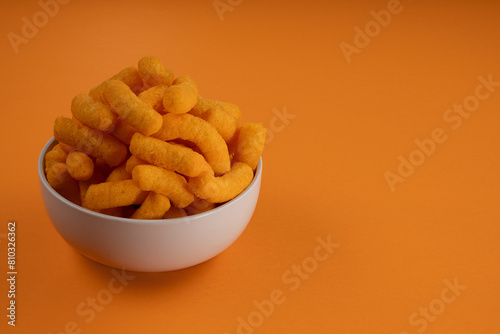 Cheese Puff Crisps/Chips in a Bowl on an Orange Background photo