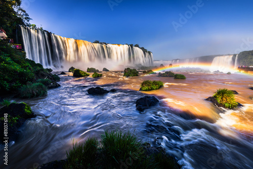 Majestic waterfall with rainbow at sunrise