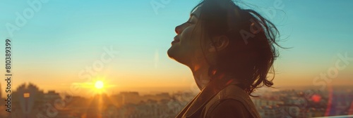The woman opens her eyes and looks out at the view. The sun is now fully risen and the sky is a clear blue. The city below is just beginning to wake up. 