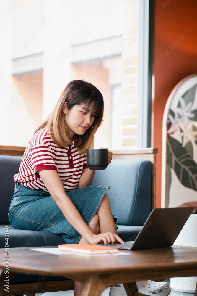 Focused young student engages with her studies on a laptop in a cozy cafe, taking a sip from her mug in a moment of contemplation. Focused young student engages with her studies on a laptop in a cozy cafe, taking a sip from her mug in a moment of contemplation.