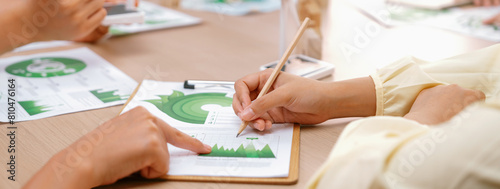 Professional businesswoman interested in invested in green businesses when he see rising graph on table with environmental document scatter around. Closeup. Focus on hand. Delineation.