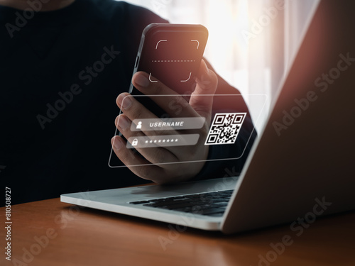 QR Code, multi factor authentication security concept. Digital scanner, graphic symbol on smartphone camera lens holding by businessman hand, scanning for login on virtual screen from laptop computer. photo