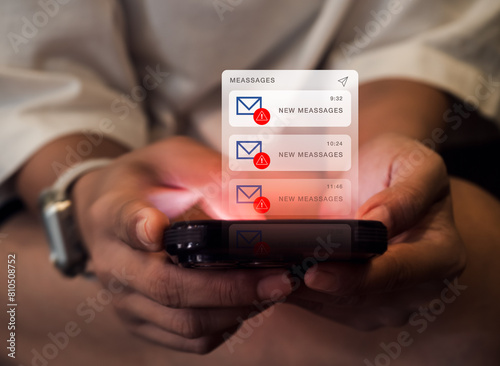 SMS spam and fake text message phishing concept. System hacked warning alert, email hack, scam malware spreading virus on messages alert virtual on mobile smart phone screen in hands, dark tone. © tete_escape