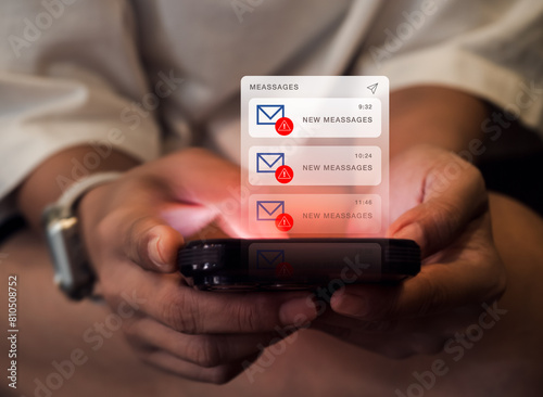 SMS spam and fake text message phishing concept. System hacked warning alert, email hack, scam malware spreading virus on messages alert virtual on mobile smart phone screen in hands, dark tone.