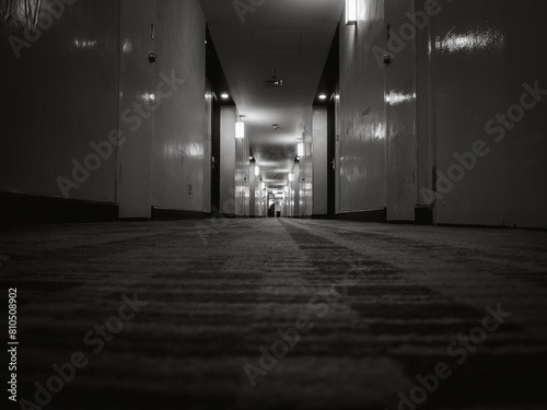 Dark mysterious corridor in hotel building, low angle shot. Door room perspective in lonely quiet apartment resident with light on black and white style. Lonely scene indoor hostel concept.